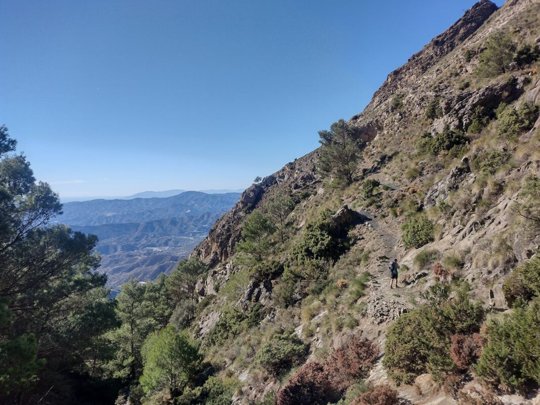 man hiking in de distance on a small mountain path on a sunny day