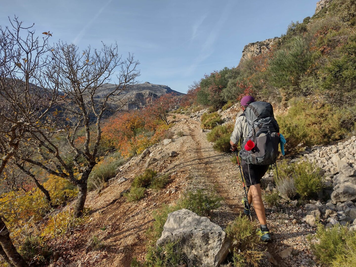 Person with big backpack hiking on small mountain path on sunny day