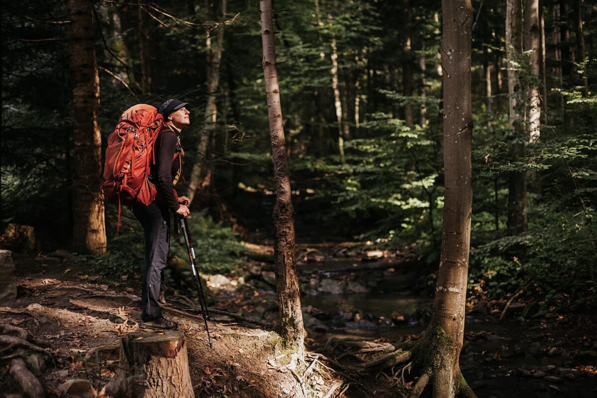 women with red backpack standing in forest