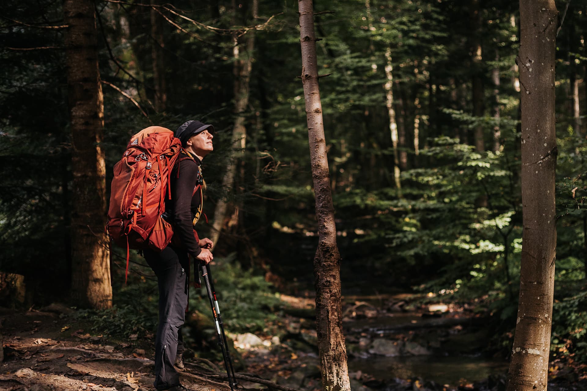 women with red backpack standing in forest