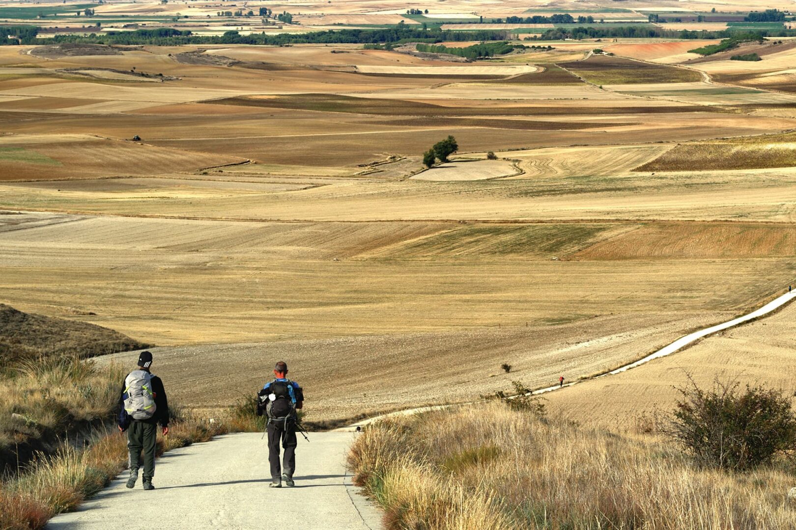 Two persons hiking on big gravel road in French countryside