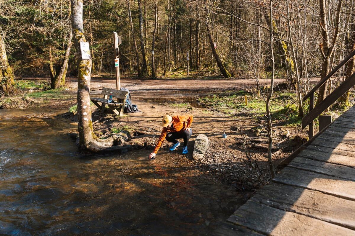 man filling a cup in river