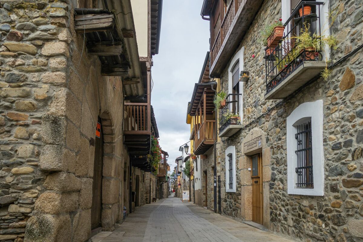 small street with stone houses with wooden balconies on both sides during cloudy day