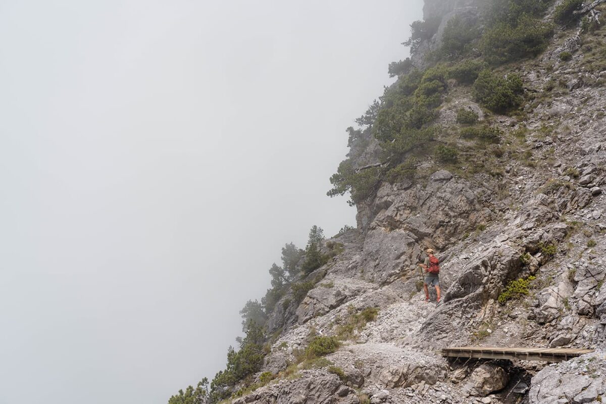 man hiking on small mountain path in mist