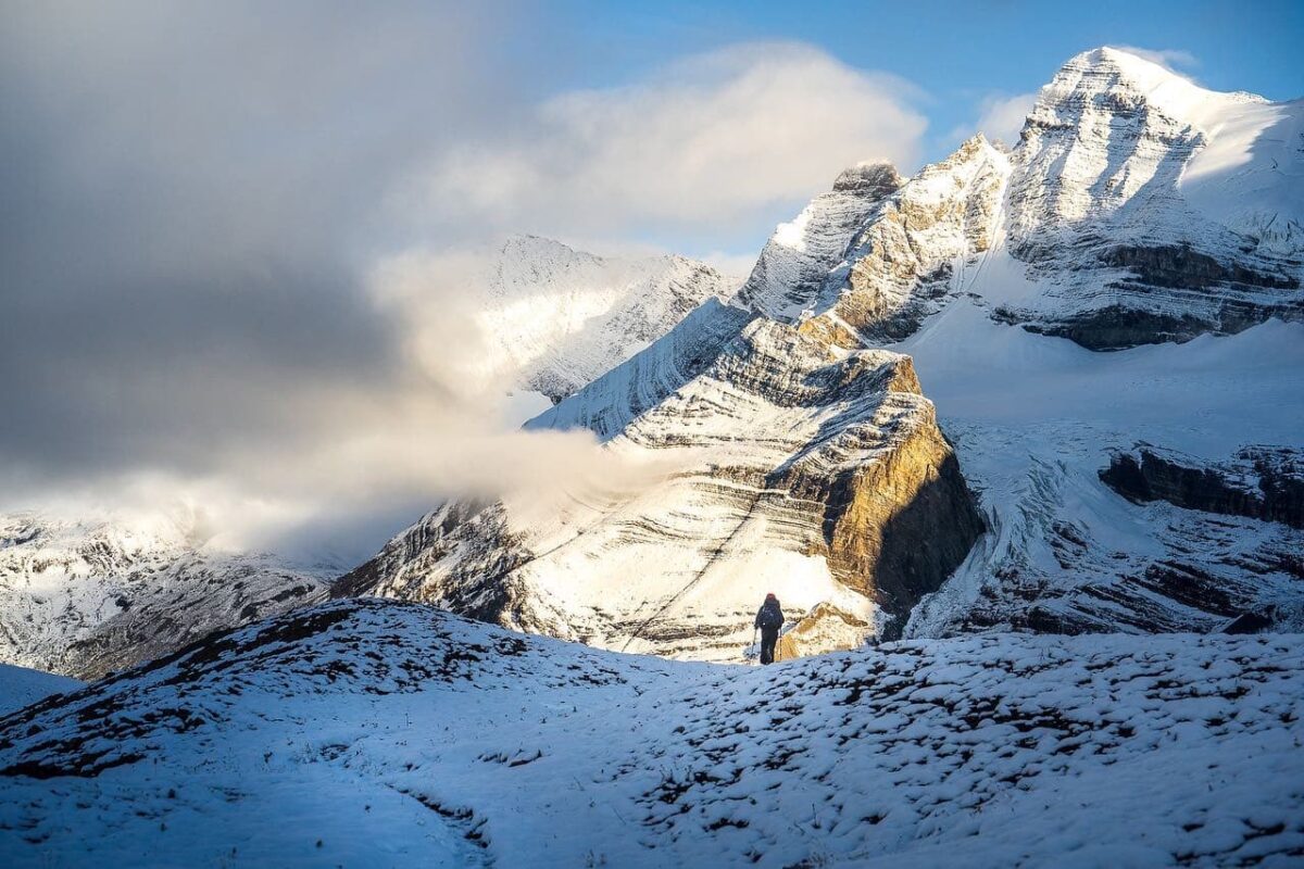 man hiking in snow towards mountain top