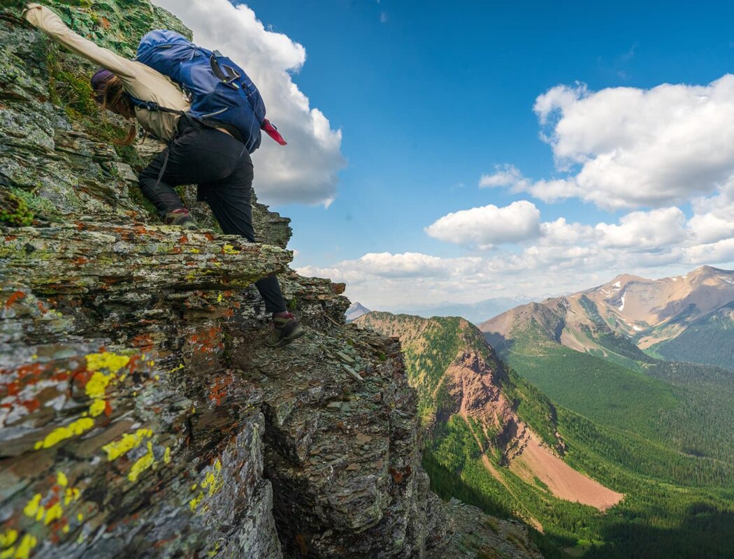 person scrambling to top of mountain