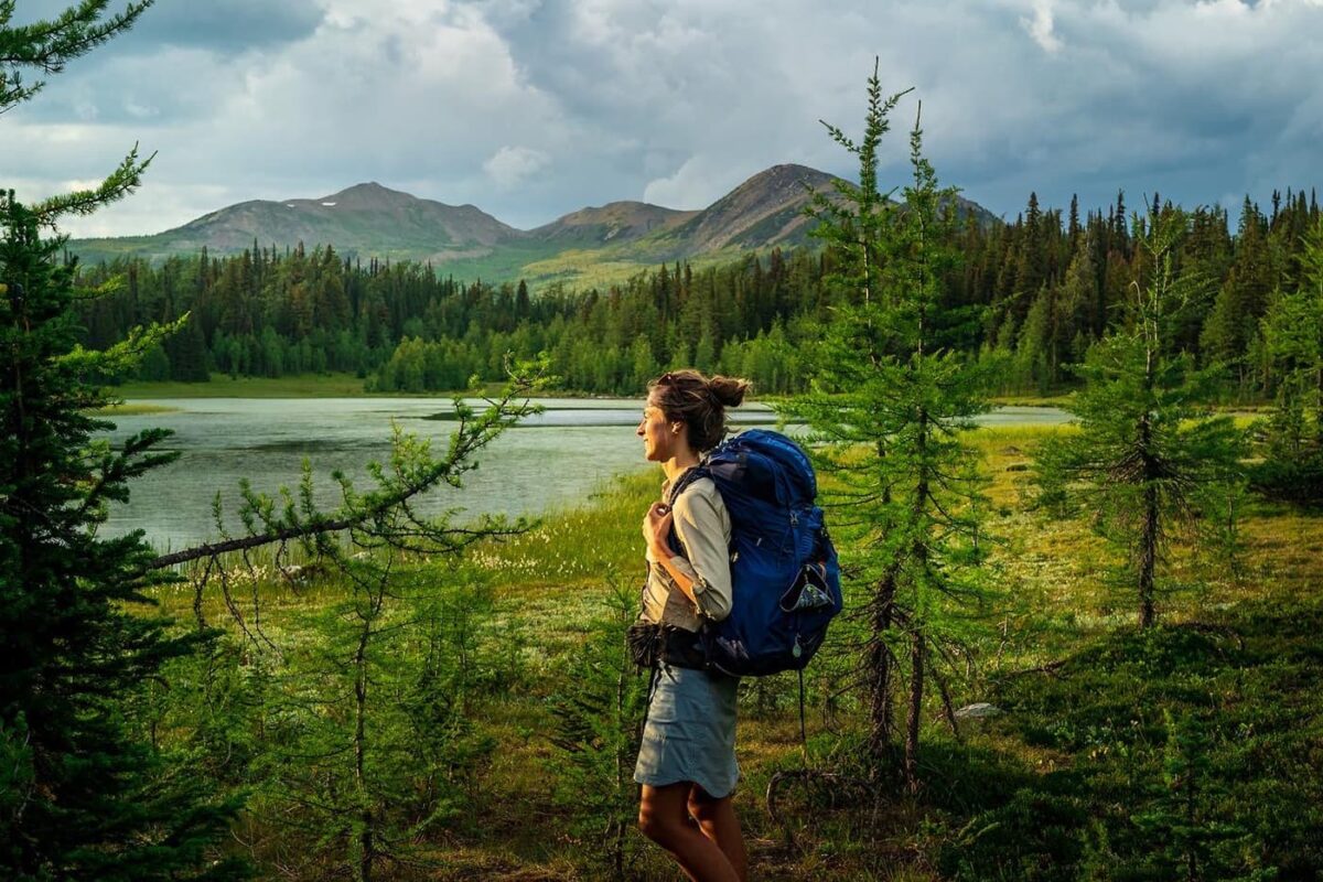 women with backpack looking out over lake