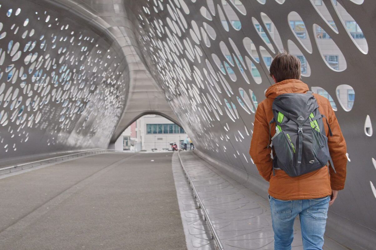 Man with backpack walking on futuristic bridge