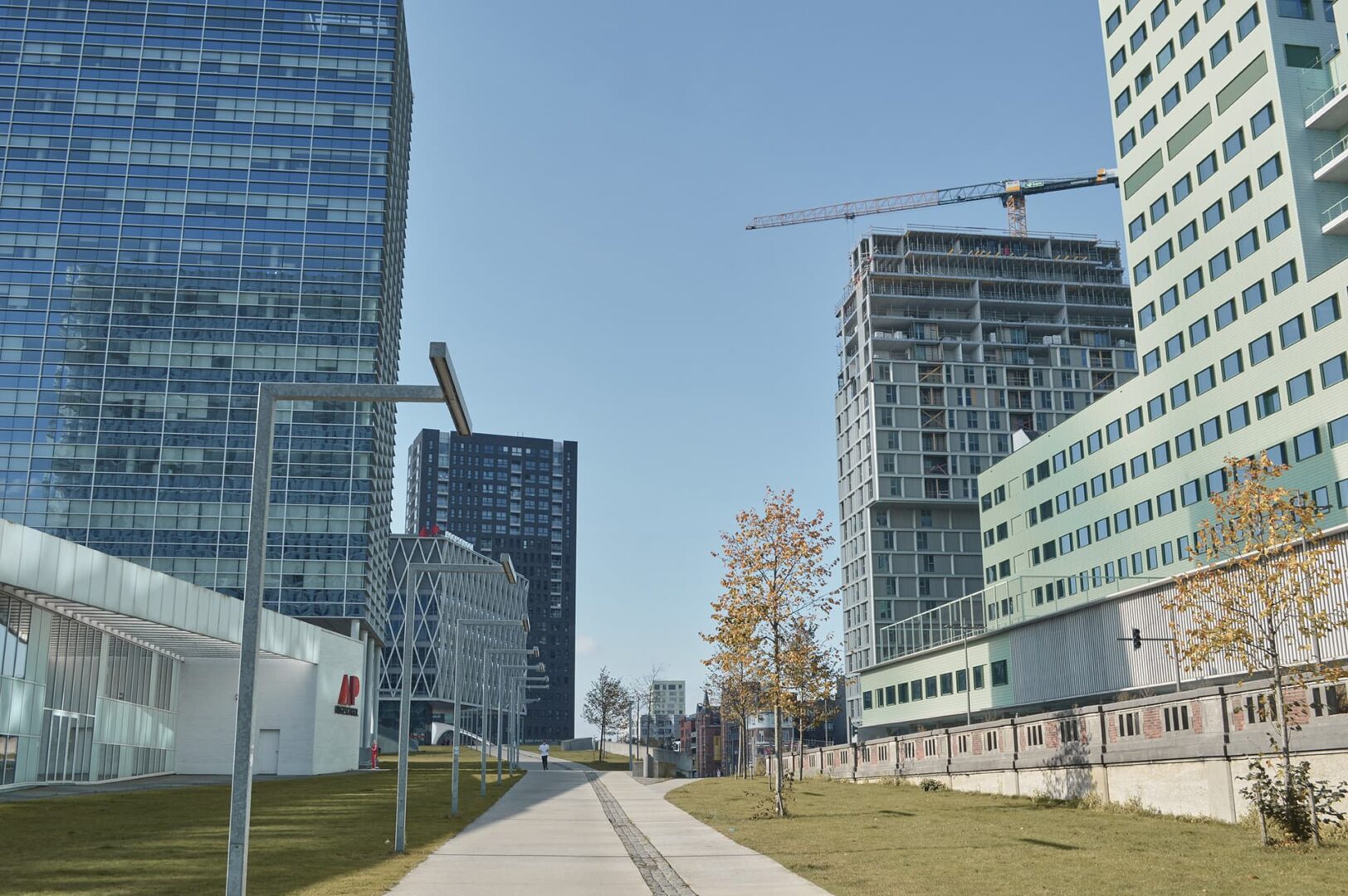 Walking path between tall glass city buildings