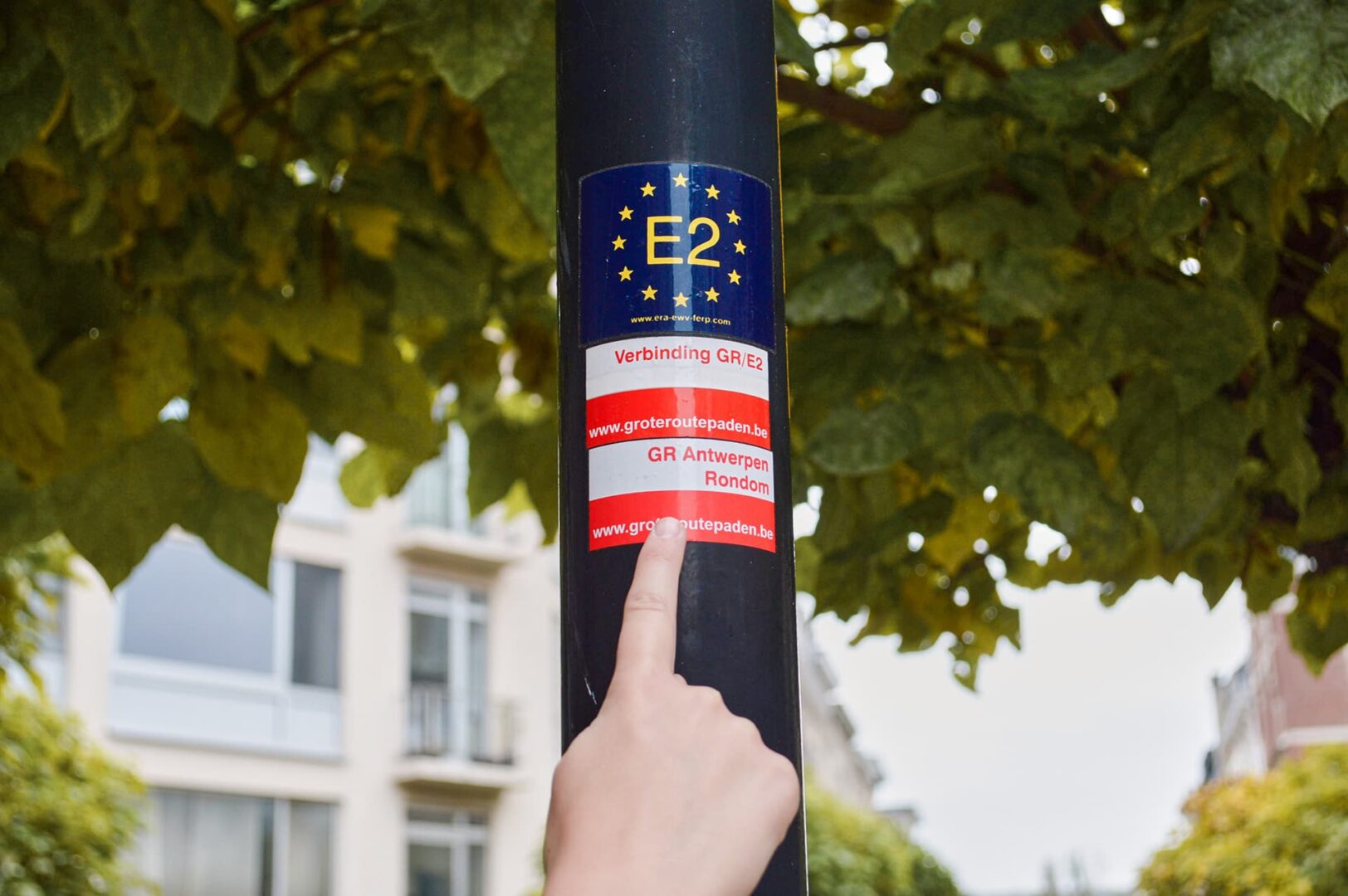 person pointing to stickers on lamp post