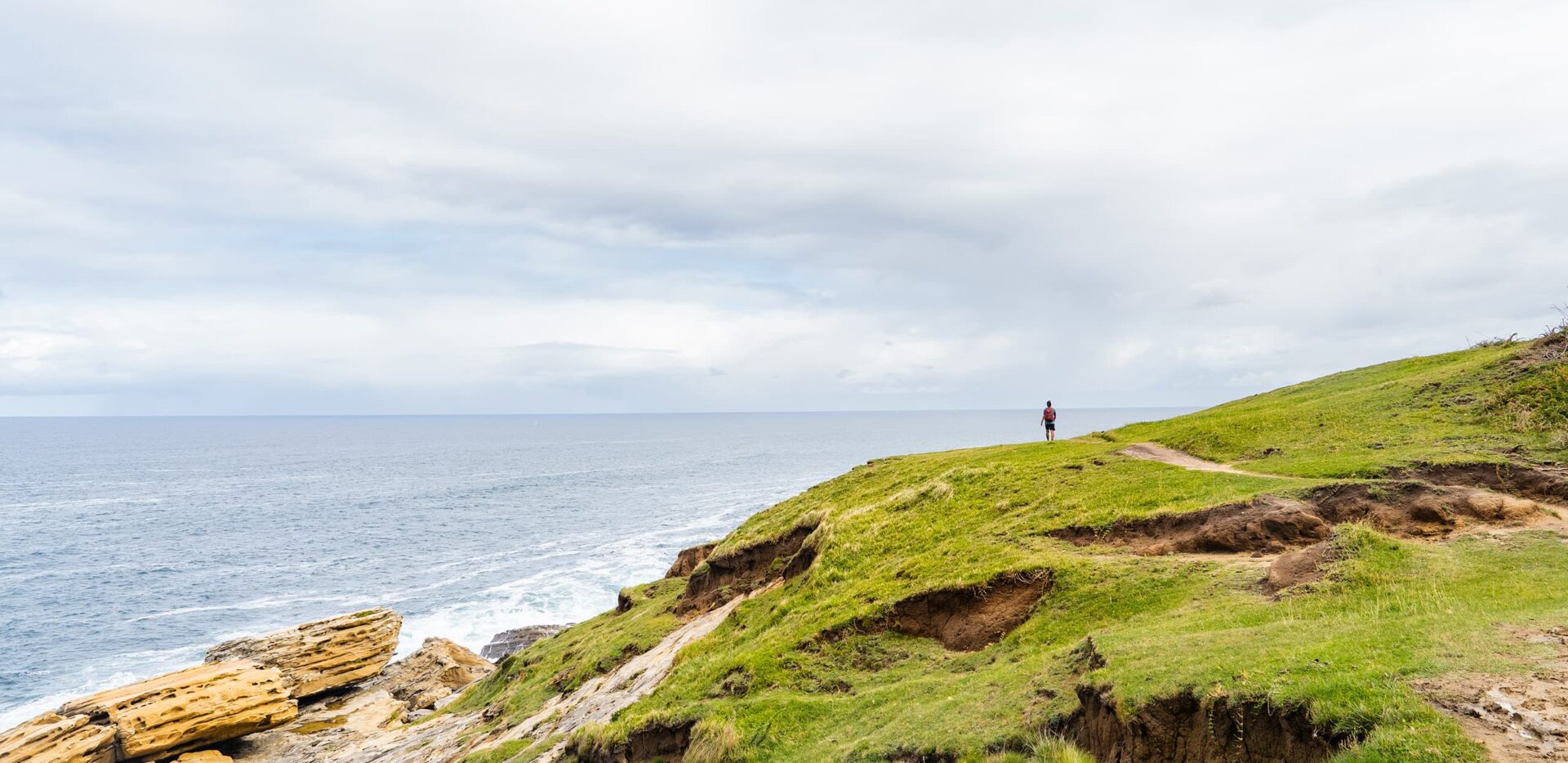 man hiking on grassy landscape near the ocean