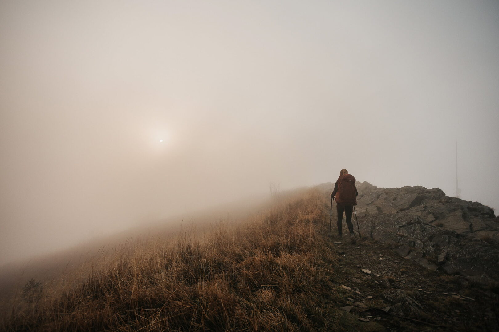 women with big backpack hiking in grassy field