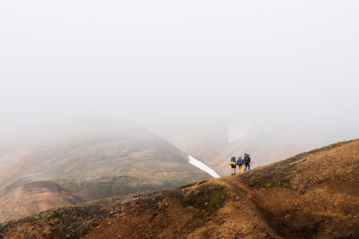 three hikers in misty mountains