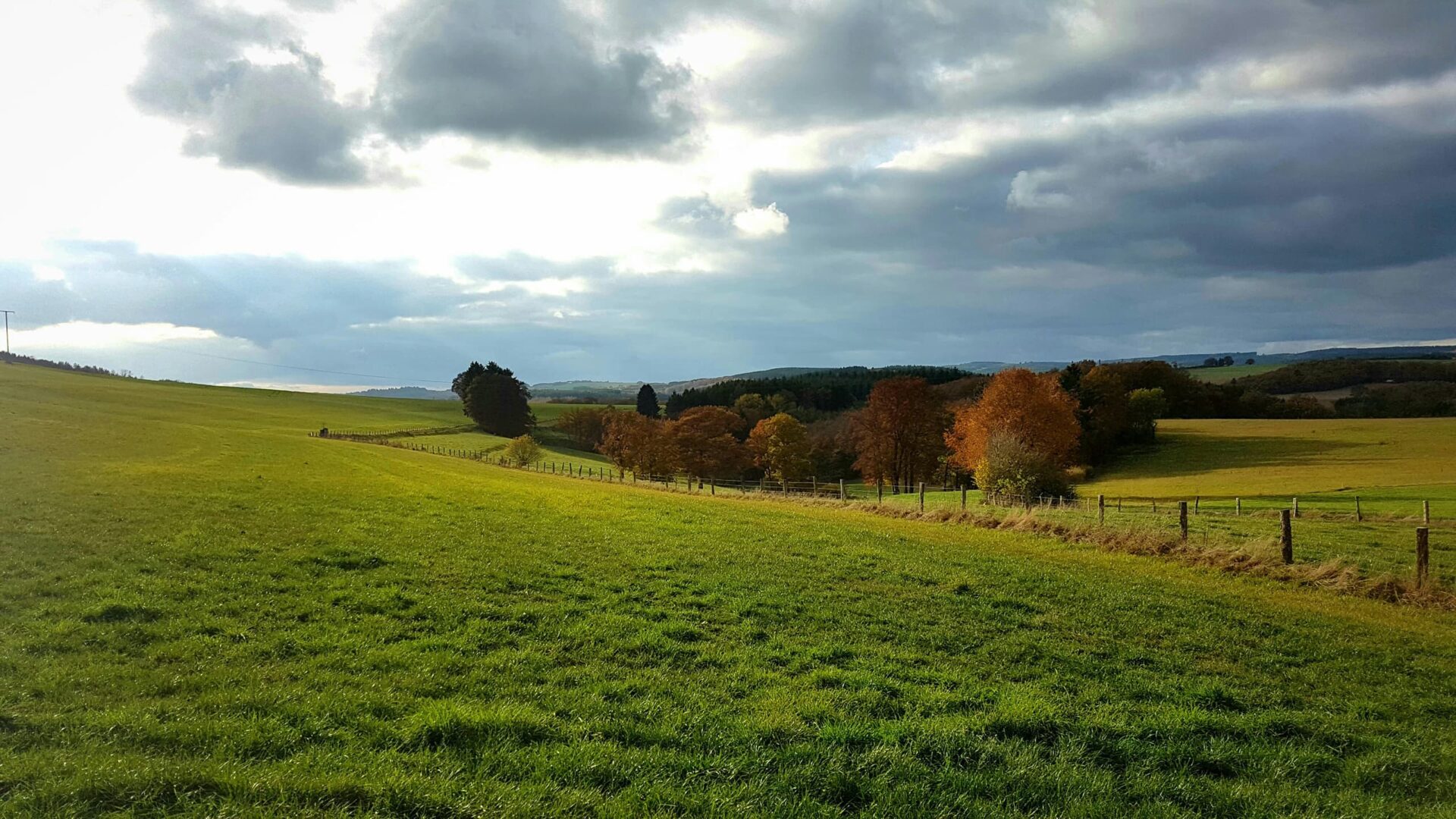 Panoramic view of green hills and countryside landscape during cloudy day