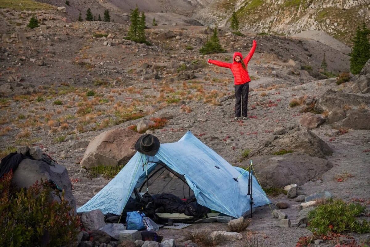 women in red jacket standing by a tent