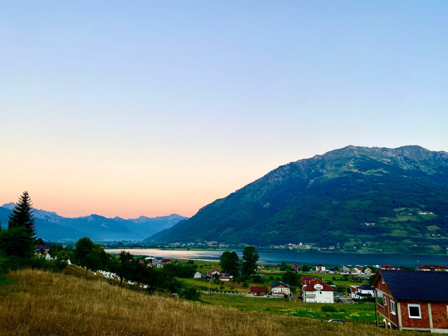 View of small town near a body of water and mountains during sunset