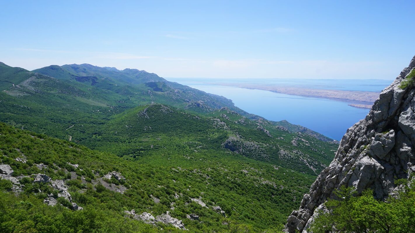 Panoramic view of grassy mountains with body of water in the background