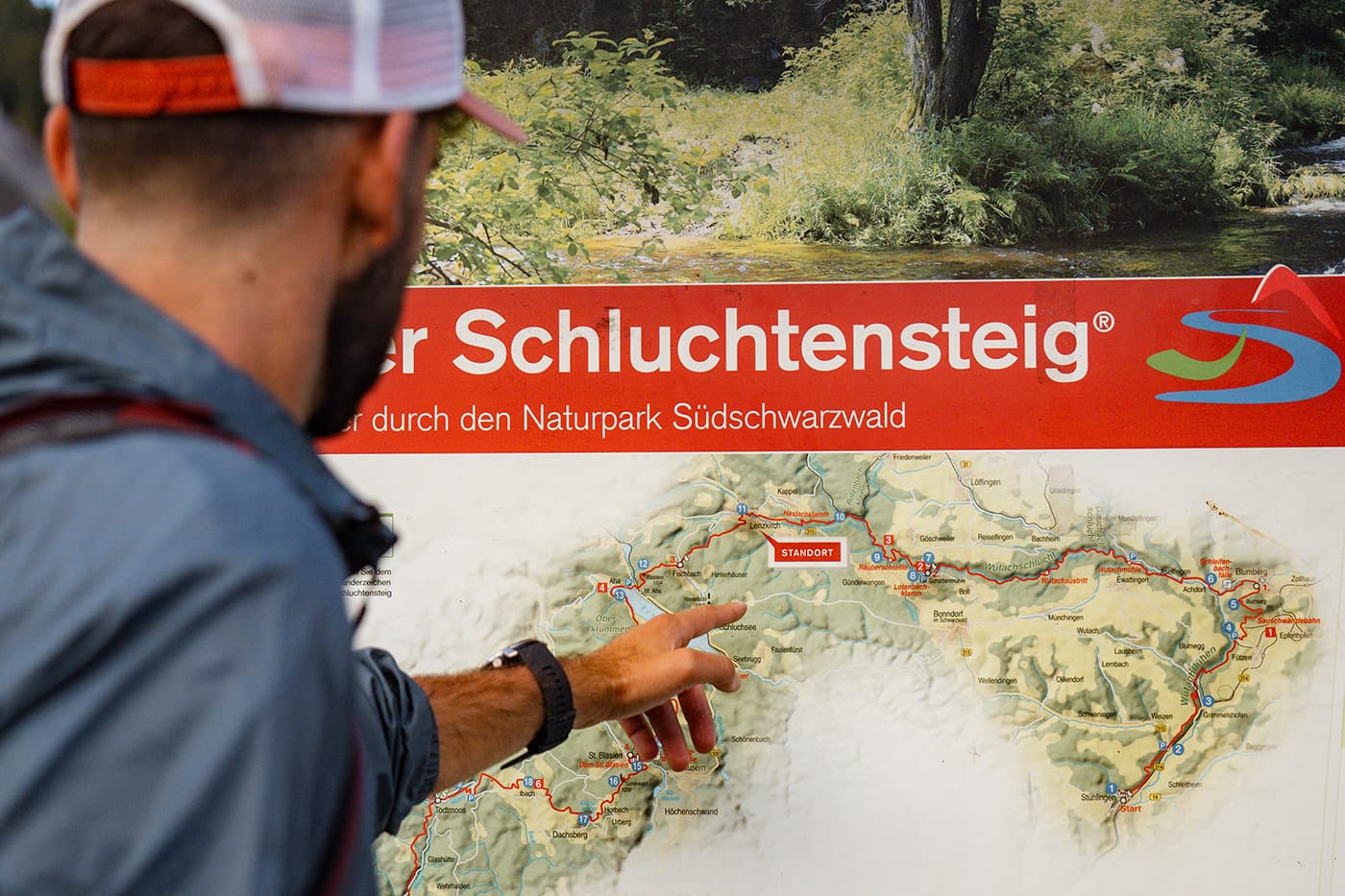 person pointing to map on road sign