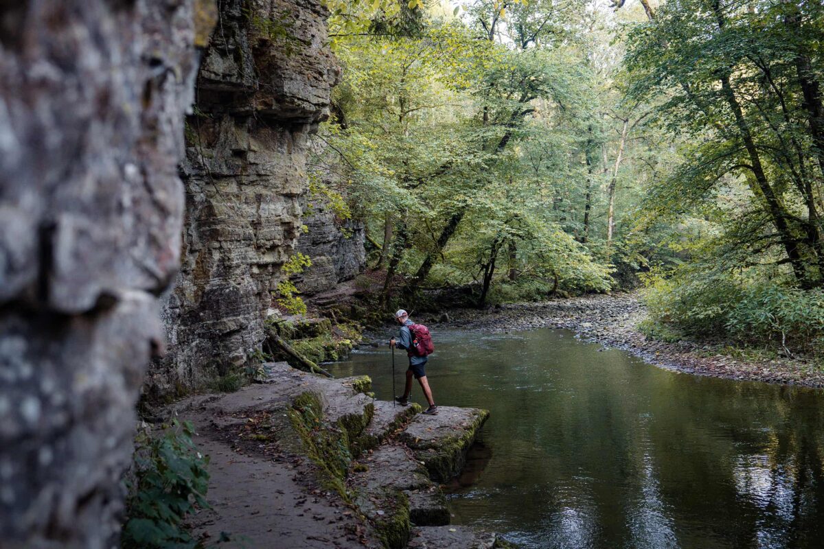 person walking near rock formation and river