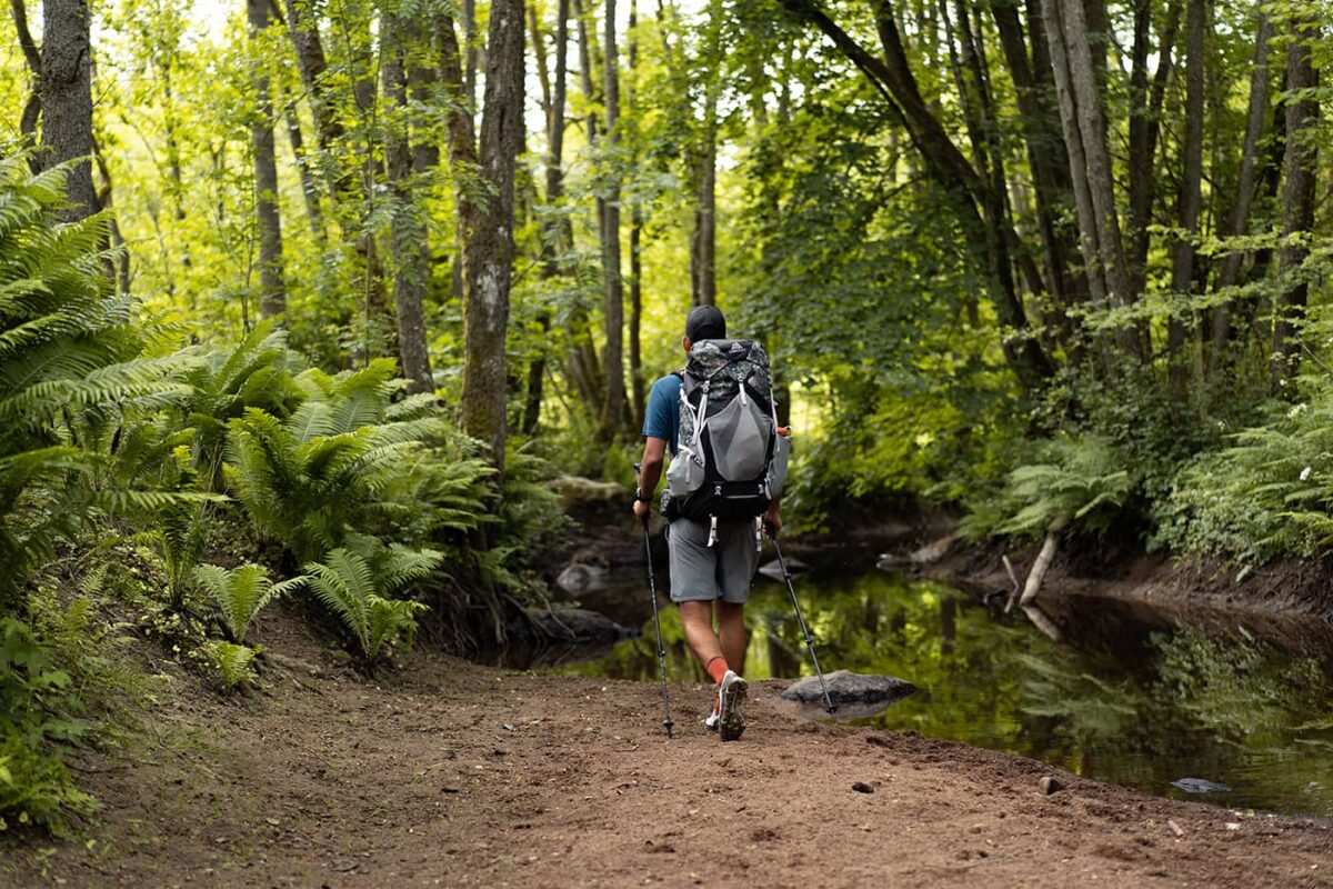 man with backpack hiking in the forest near river