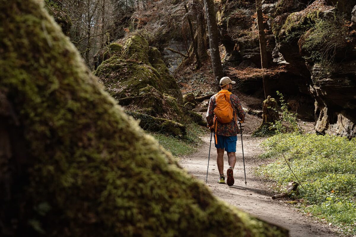 man hiking on forest path near rock formation