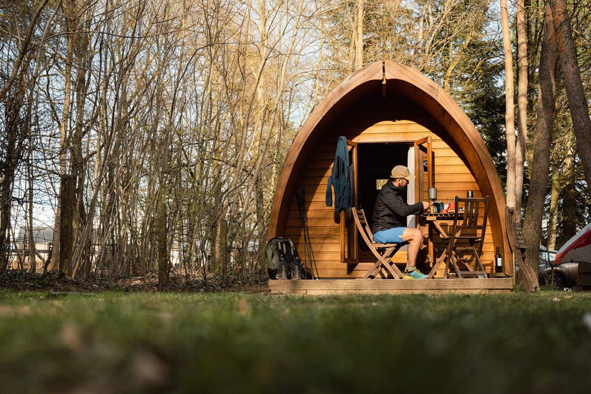 man sitting at wooden cabin in the forest