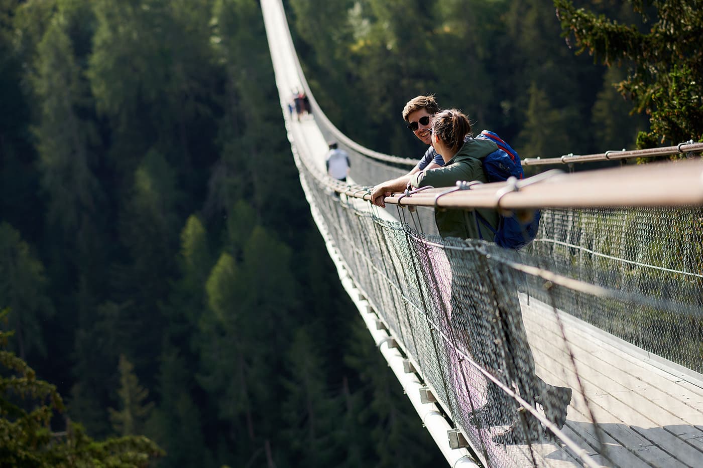 two persons standing on suspension bridge over valley