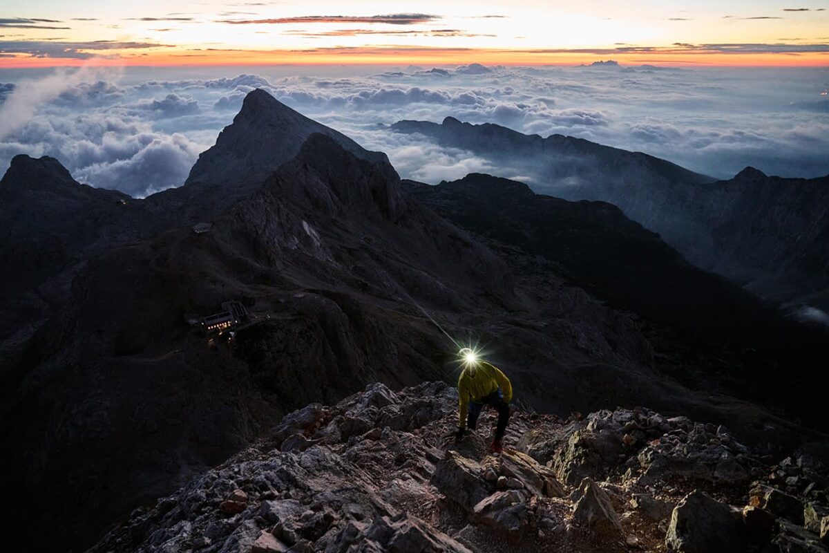 hiker with his headlamp on during sunrise