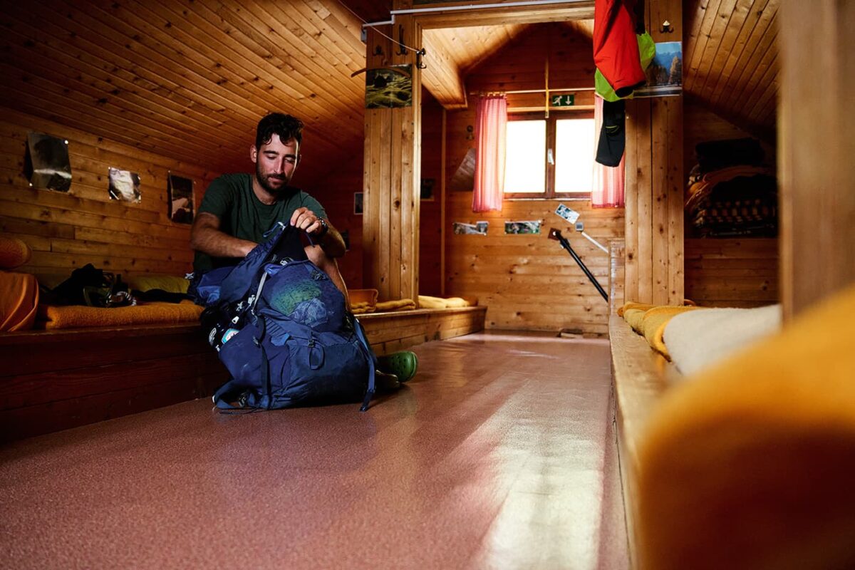 man looking through his backpack in mountain hut