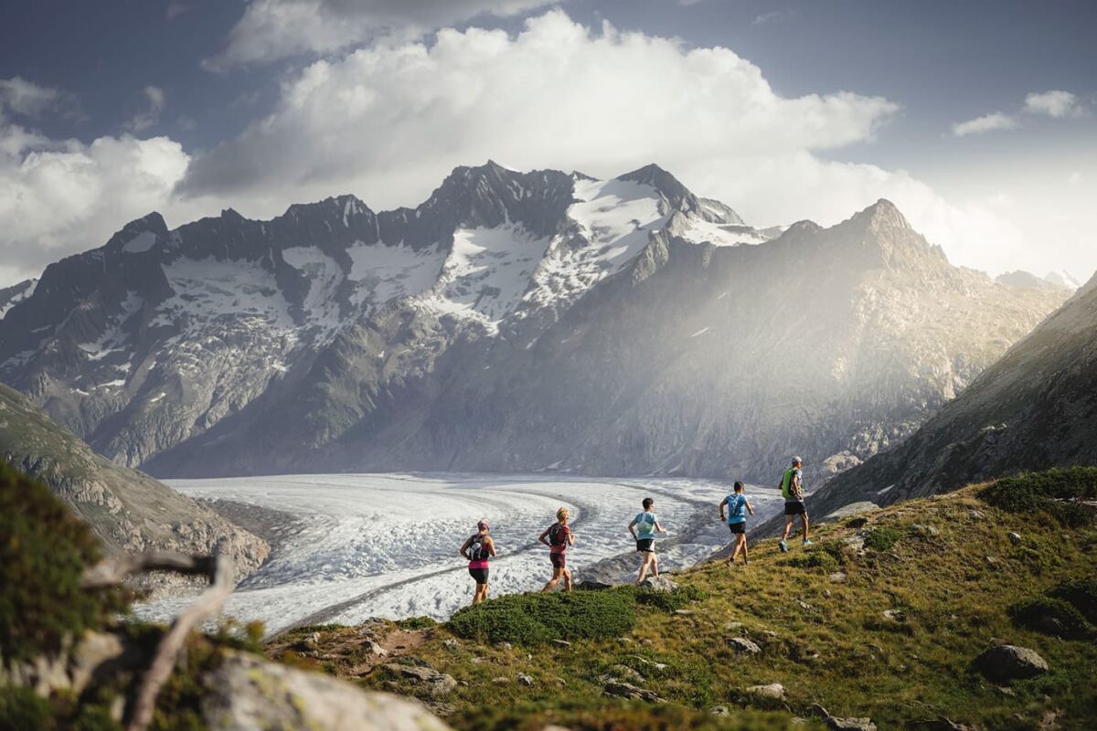 group of people trail running in front of glacier