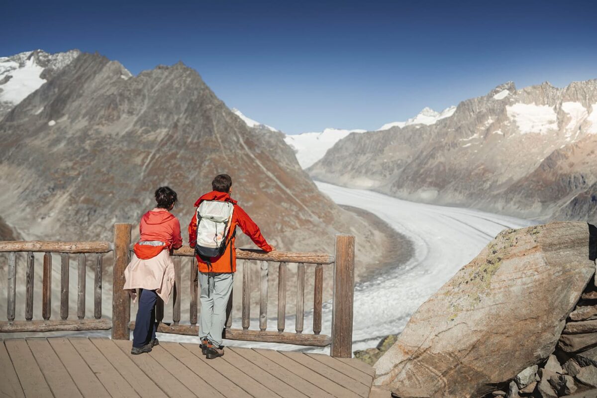 two persons at vantage point looking at glacier