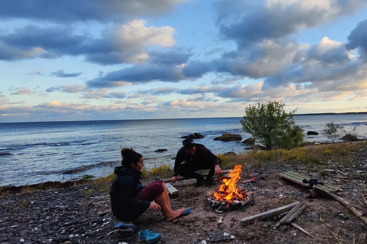 two persons making fire by the water