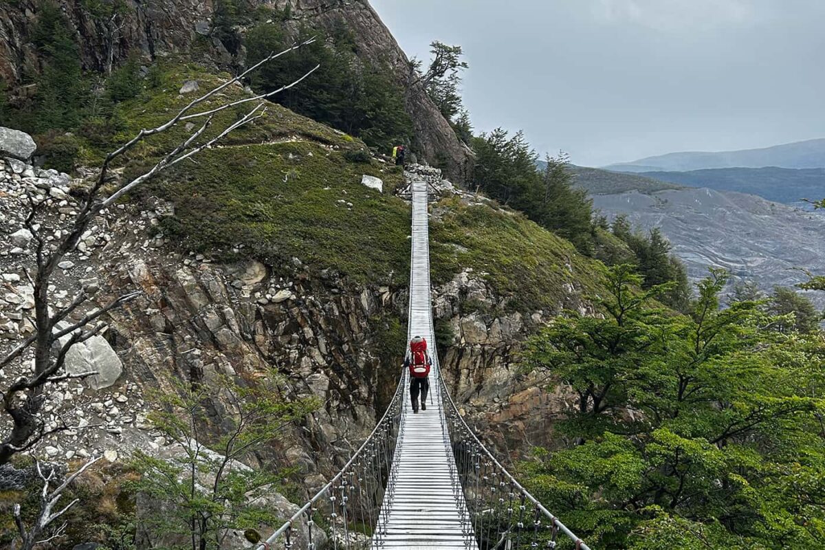 man hiking on suspension bridge