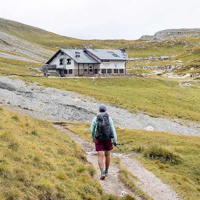 man hiking towards mountain hut