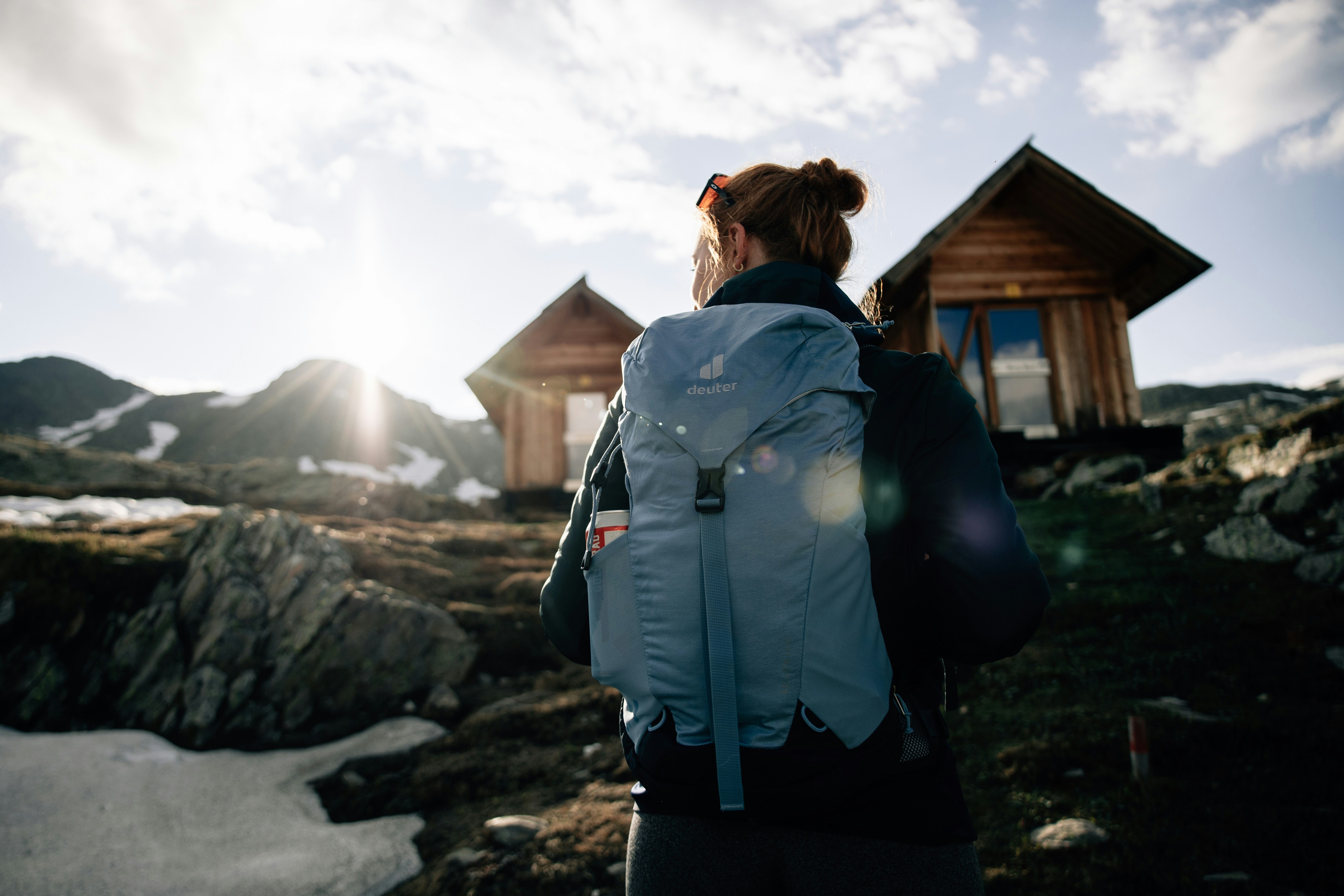 women with backpack near mountain hut