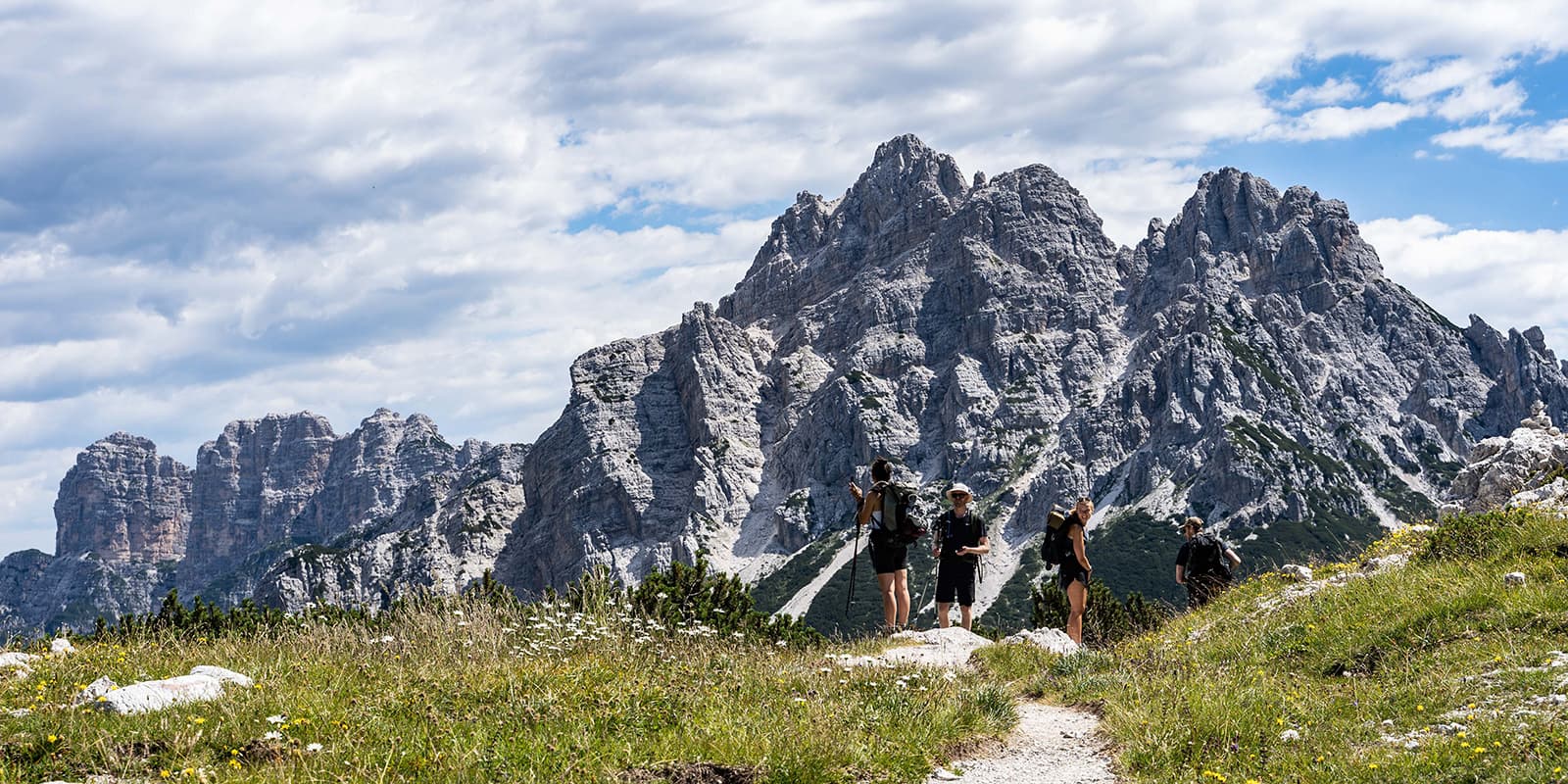 group of hikers in front of rugged mountain peaks in Dolomites