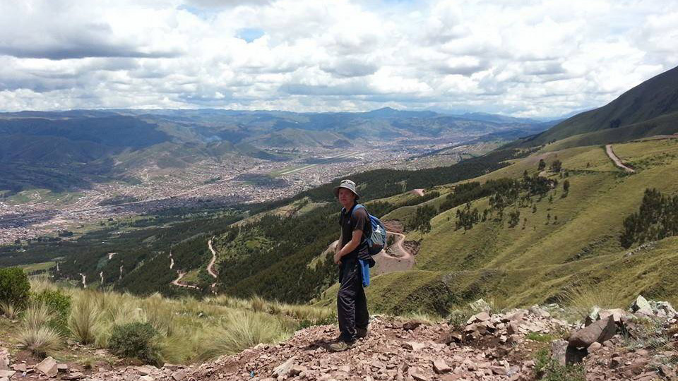 man standing on vantage point looking over mountains and city below