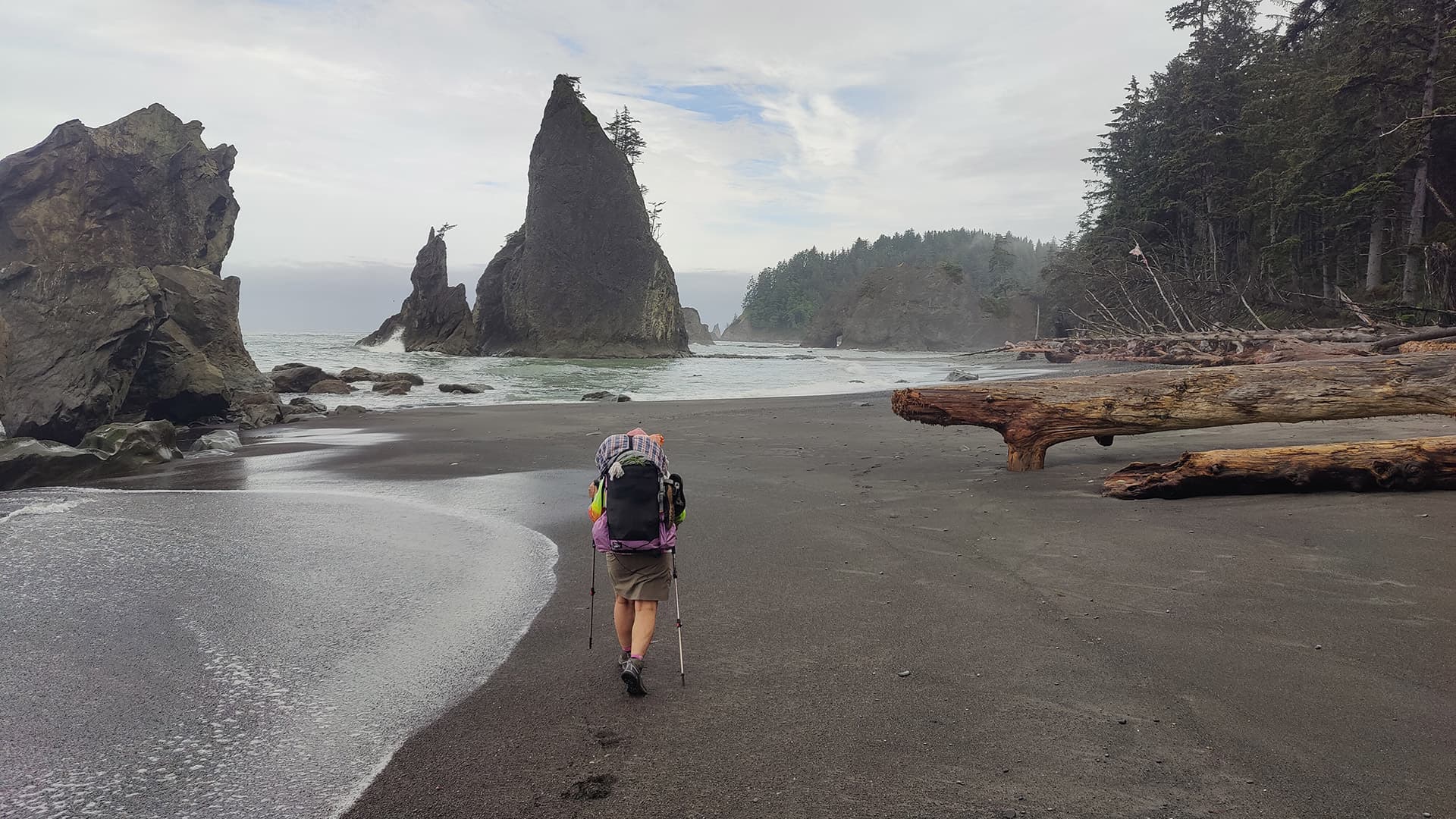 person hiking on beach with big backpack