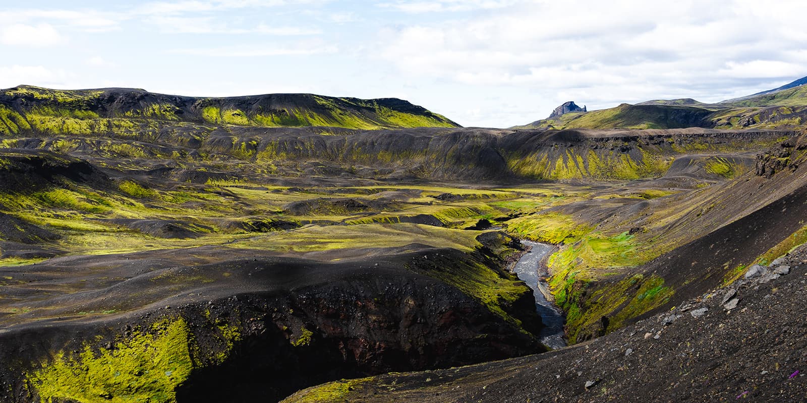 river flowing in black and green landscape of Iceland