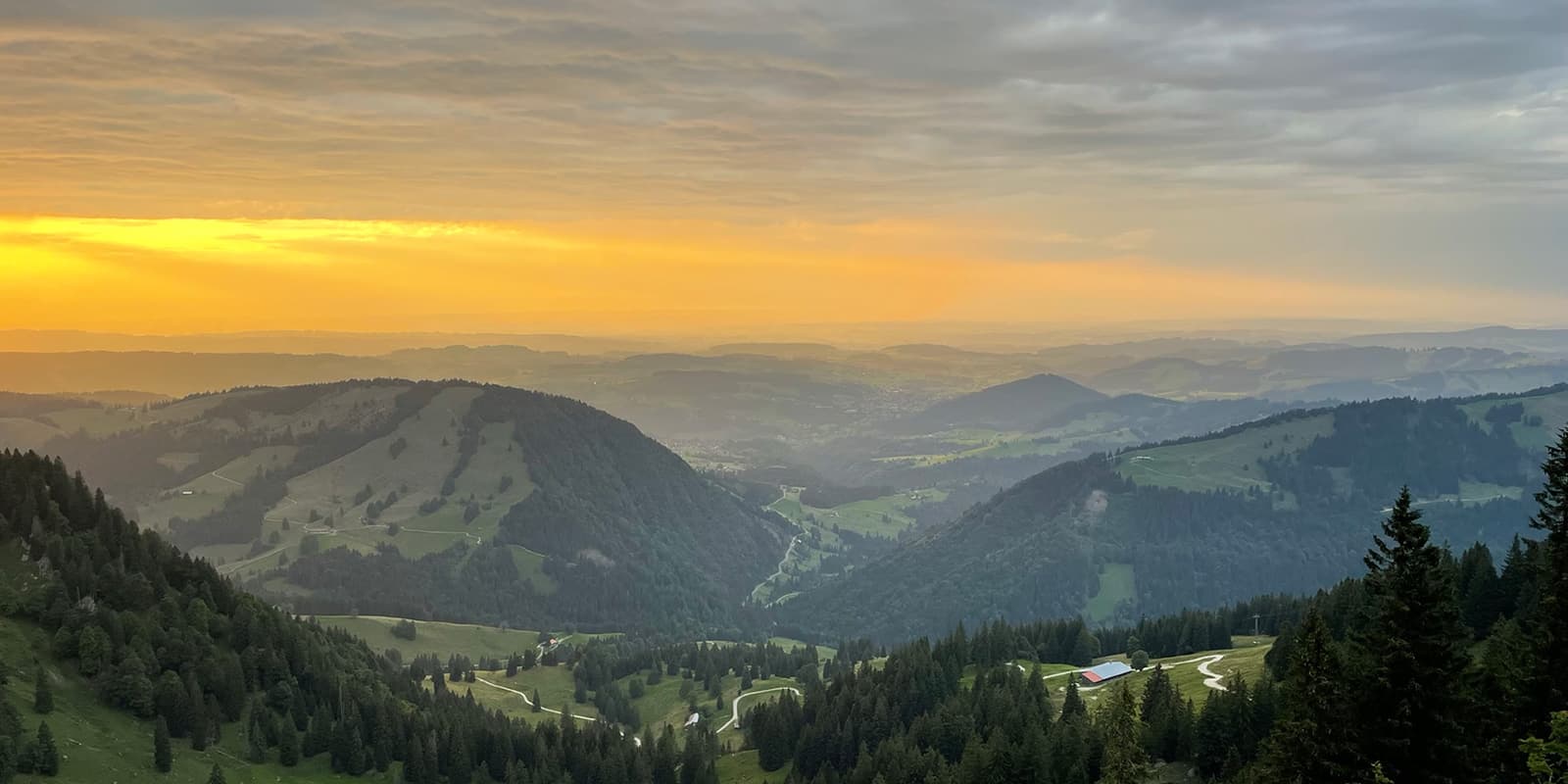 set of green hills in the distance during sunset in the German alps