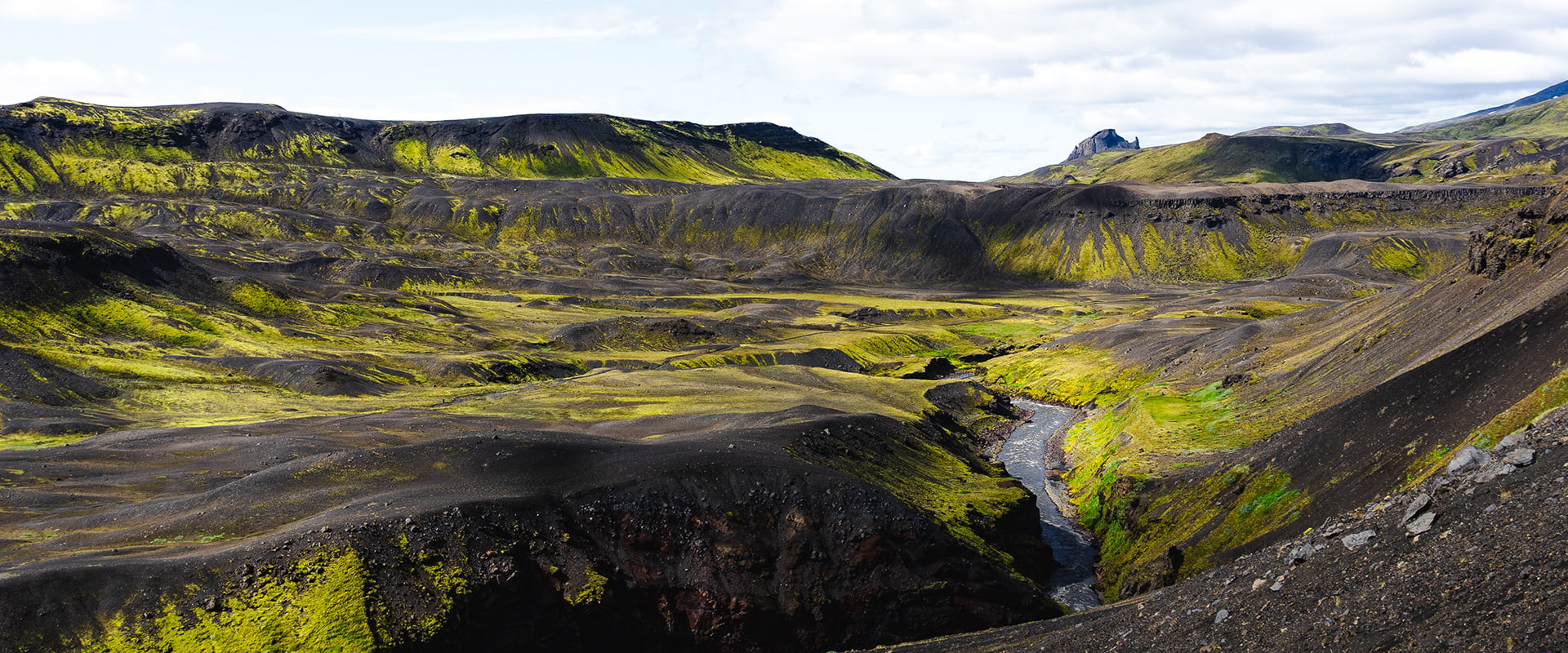 river flowing in black and green landscape of Iceland