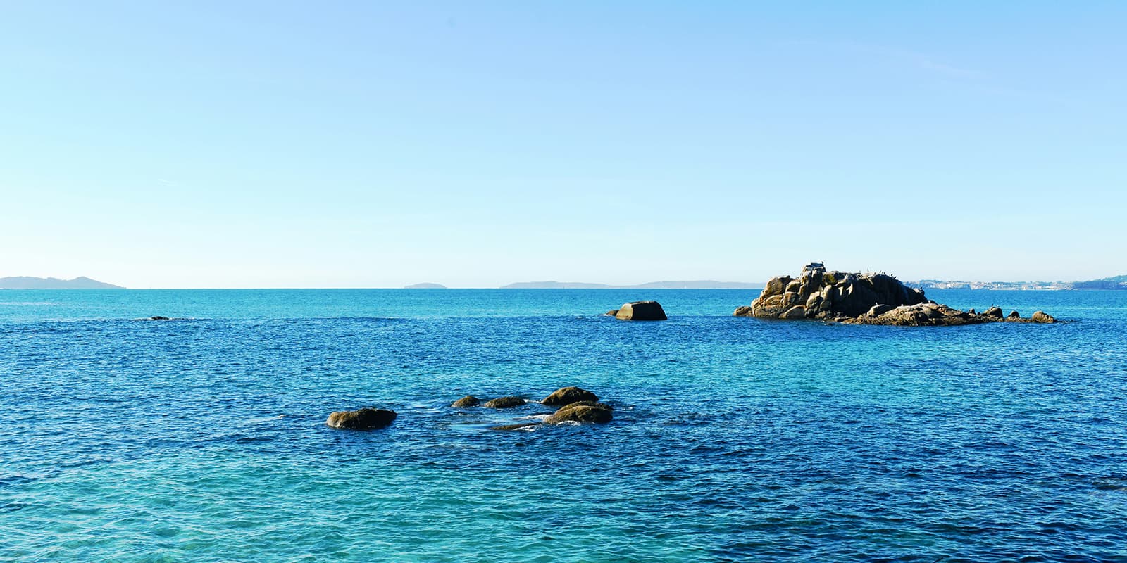 blue ocean with some rocks sticking out