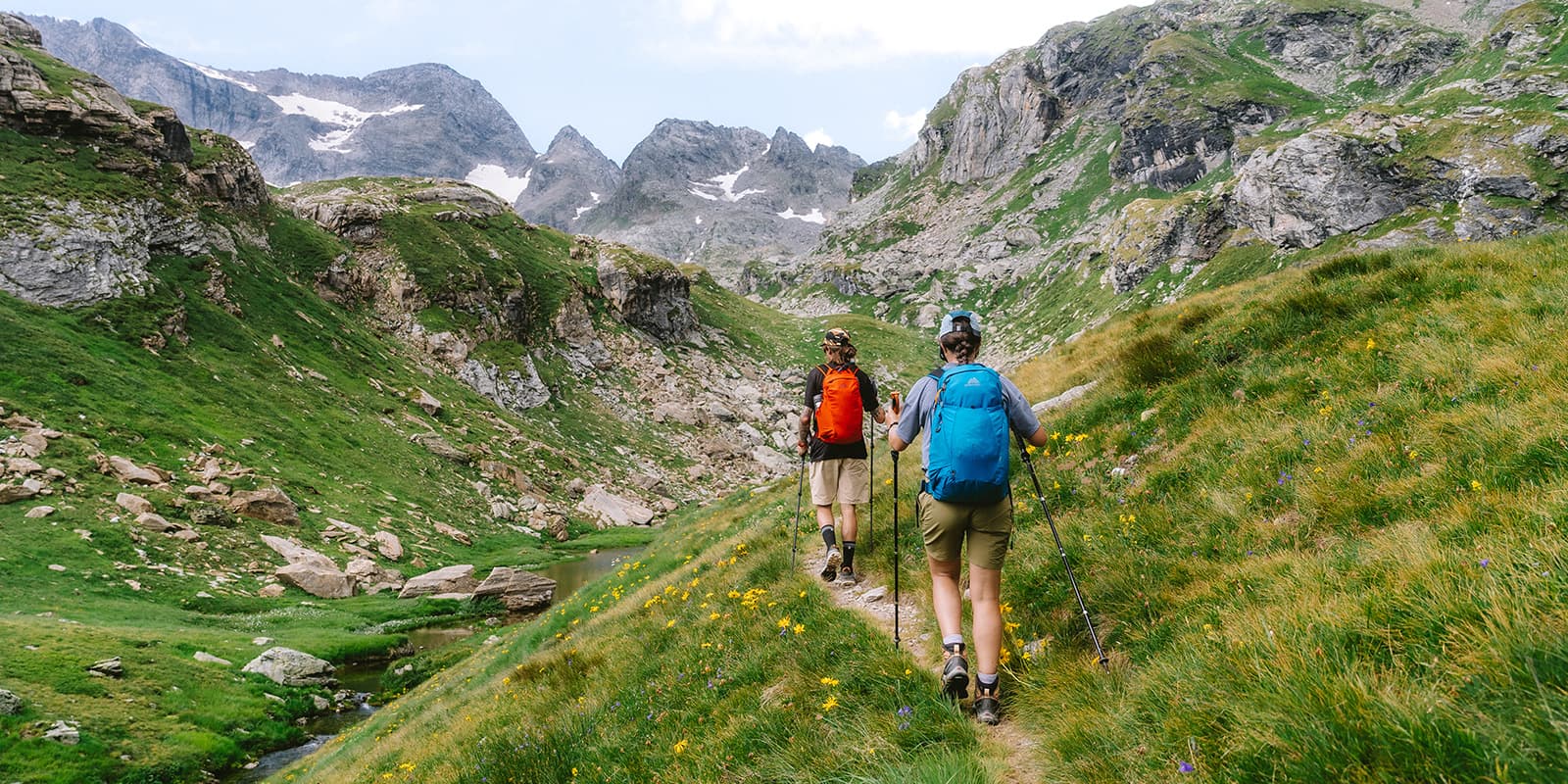 two persons hiking on small mountain path in Swiss alps