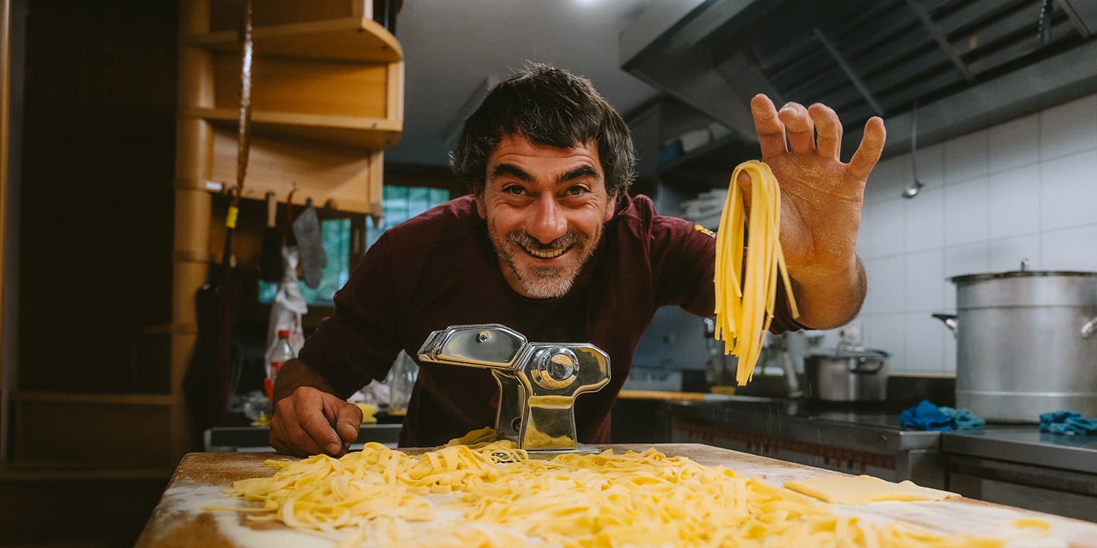 person holding freshly made pasta in kitchen