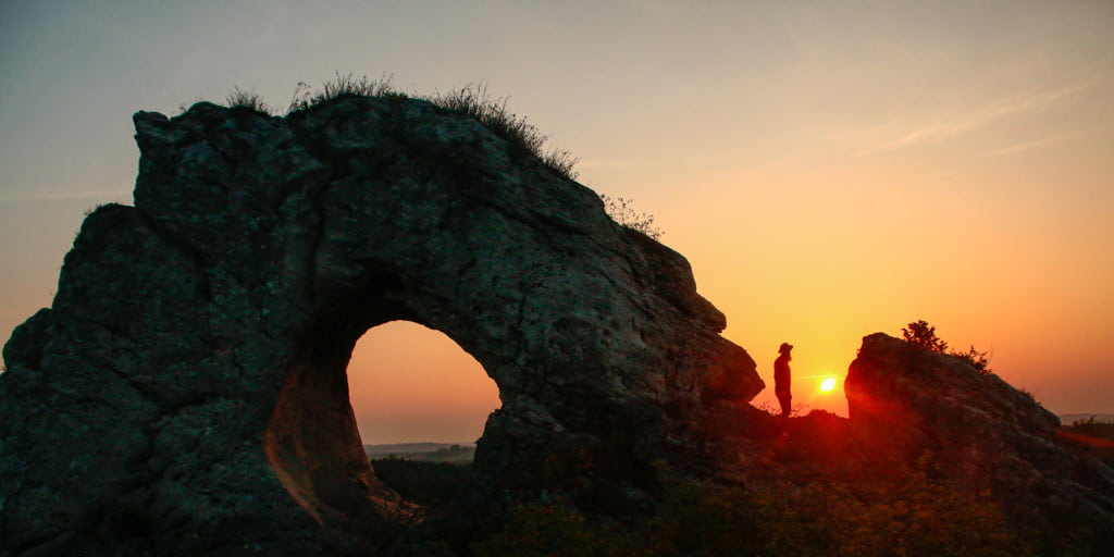 person looking at sunset near rocks