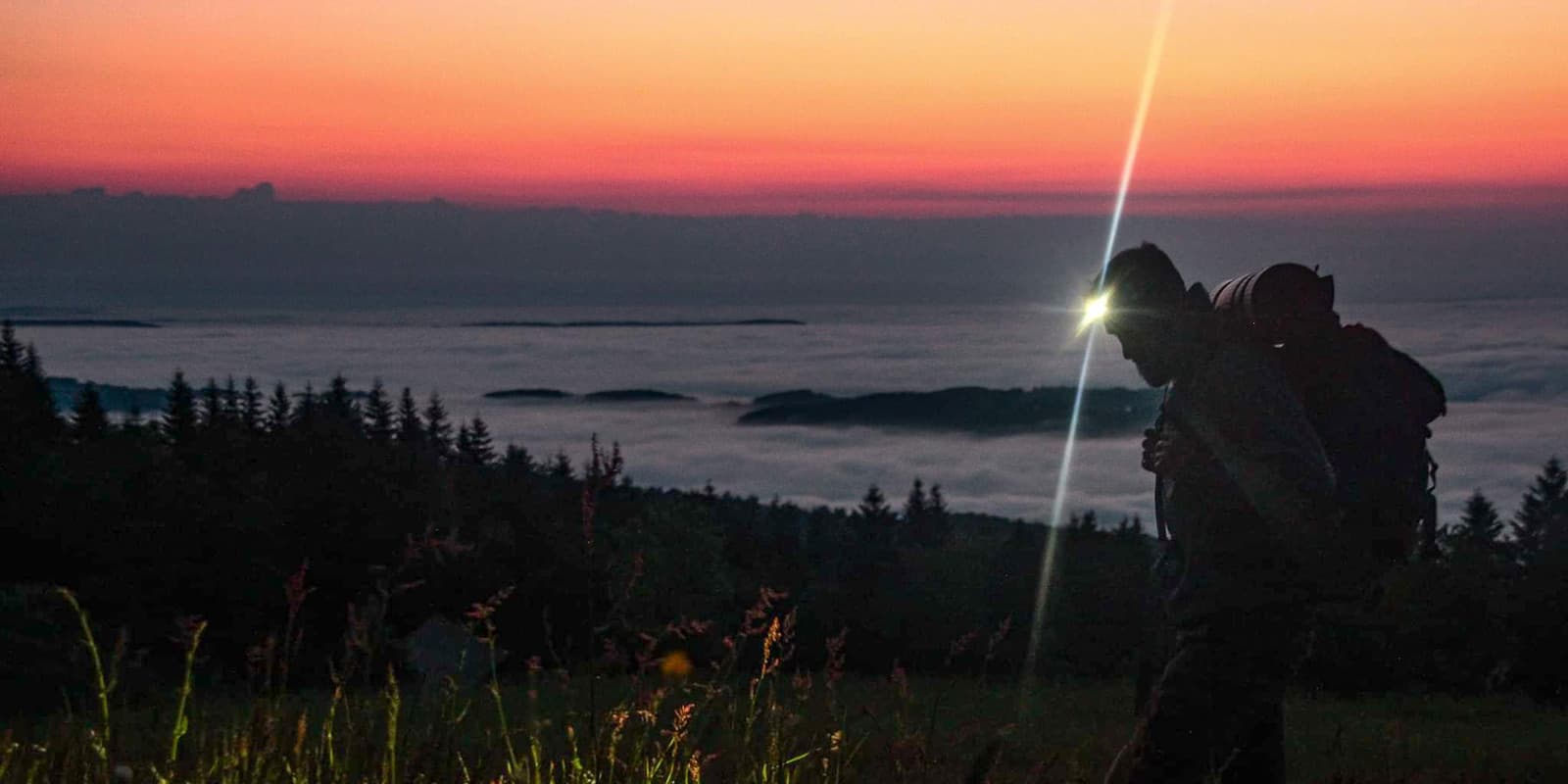 man hiking during sunset with headlight