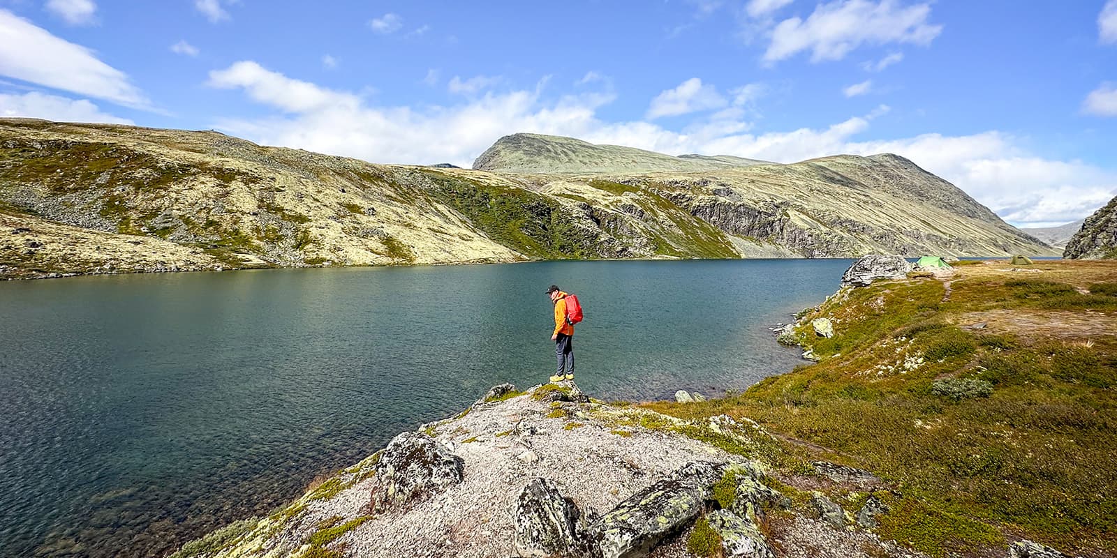 man standing near mountain lake