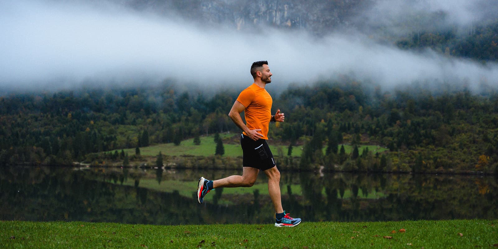 man running on grassy surface near body of water