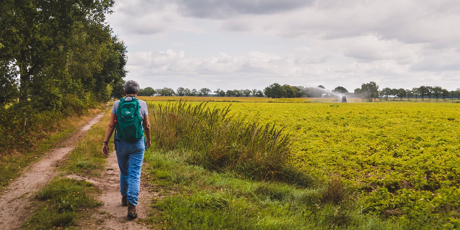 women hiking next to farm field on the Kempentocht