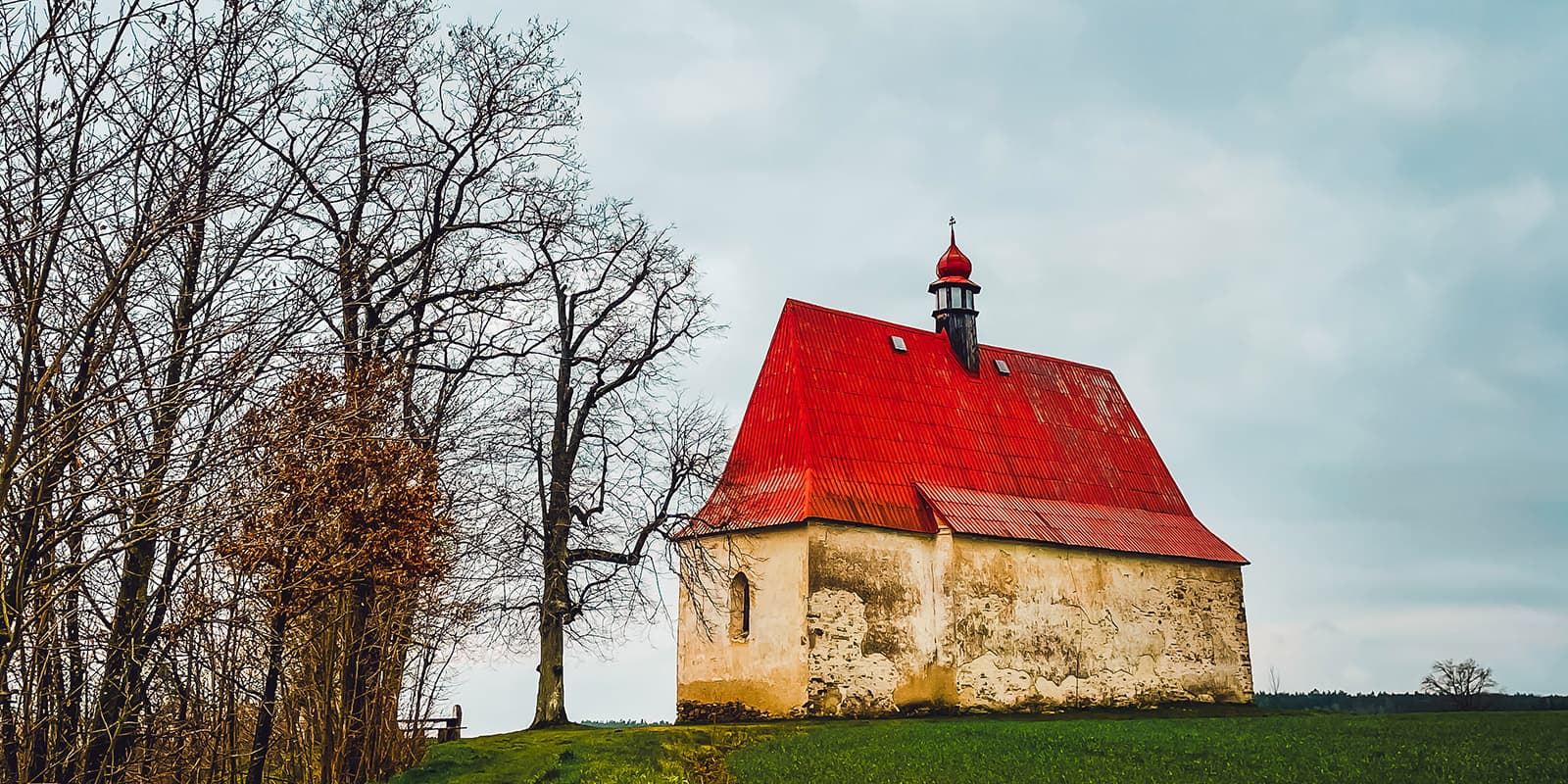 old church with red roof in field